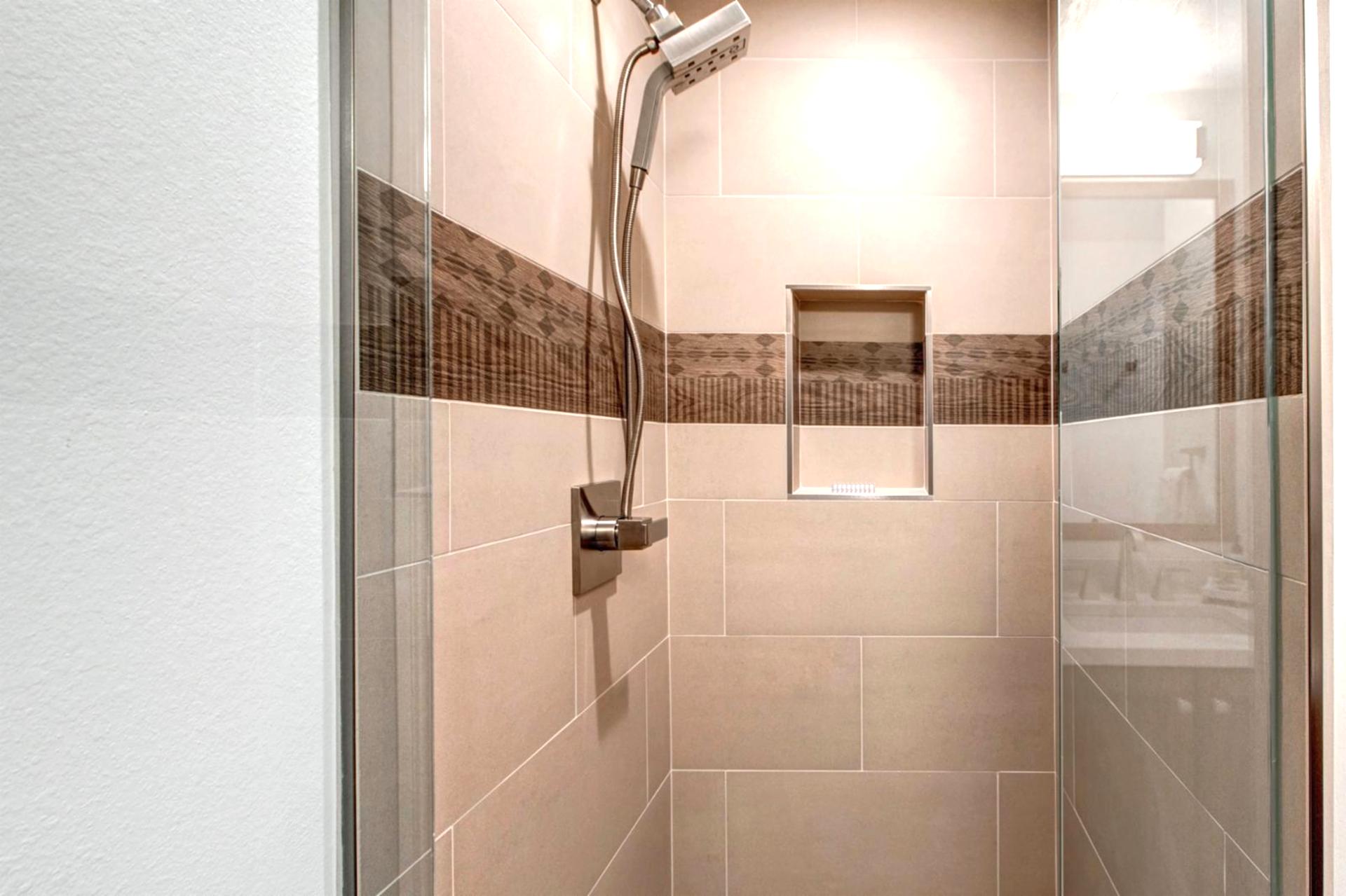 Neutral tile and glass doors elevate the walk-in shower in this main-level guest bath.