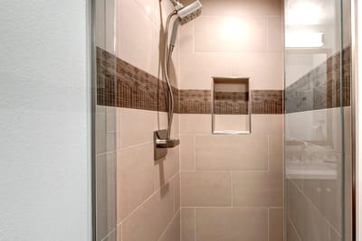 Neutral tile and glass doors elevate the walk-in shower in this main-level guest bath.