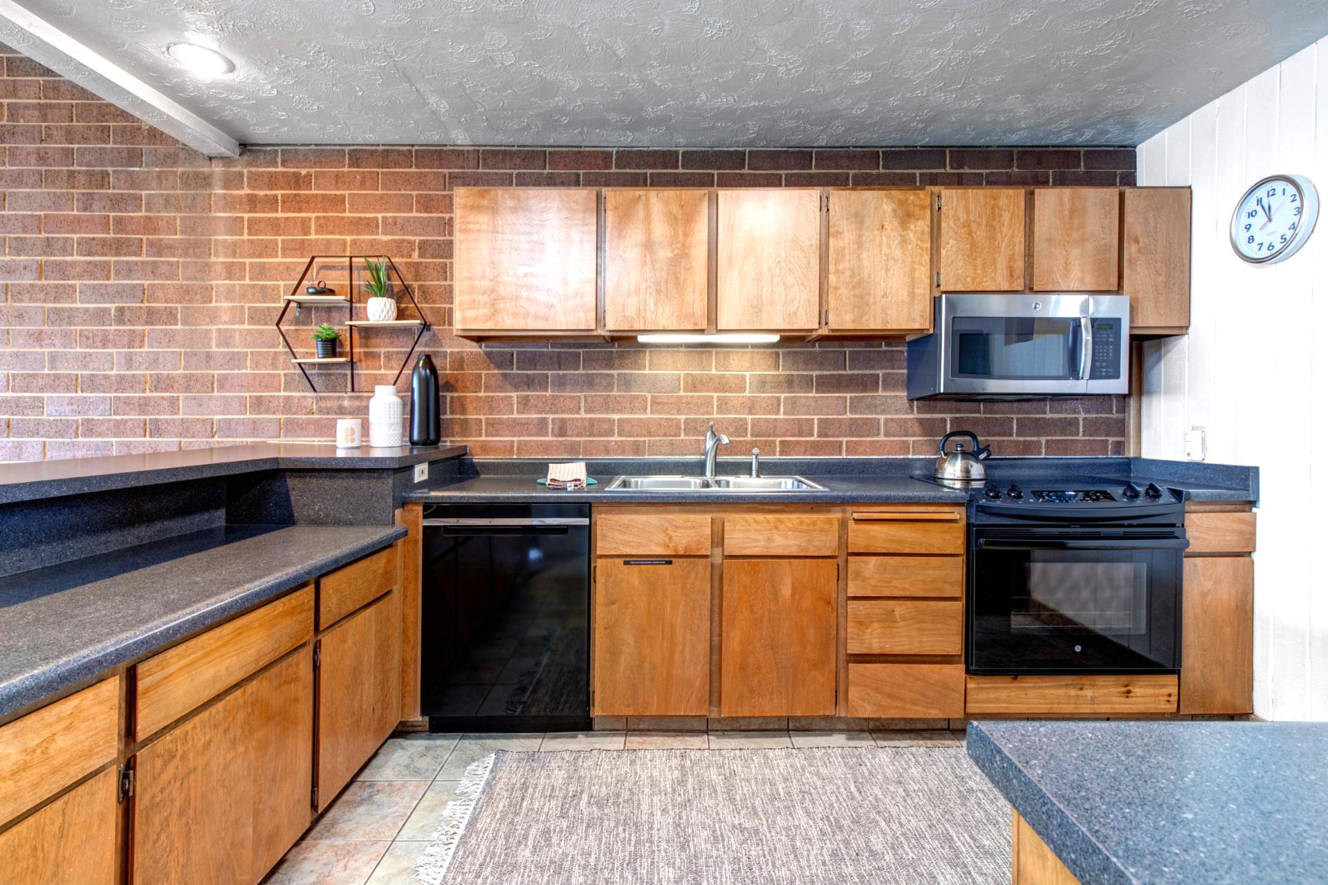 Fully equipped kitchen with warm wood cabinets, modern appliances, and bar seating for easy prep.