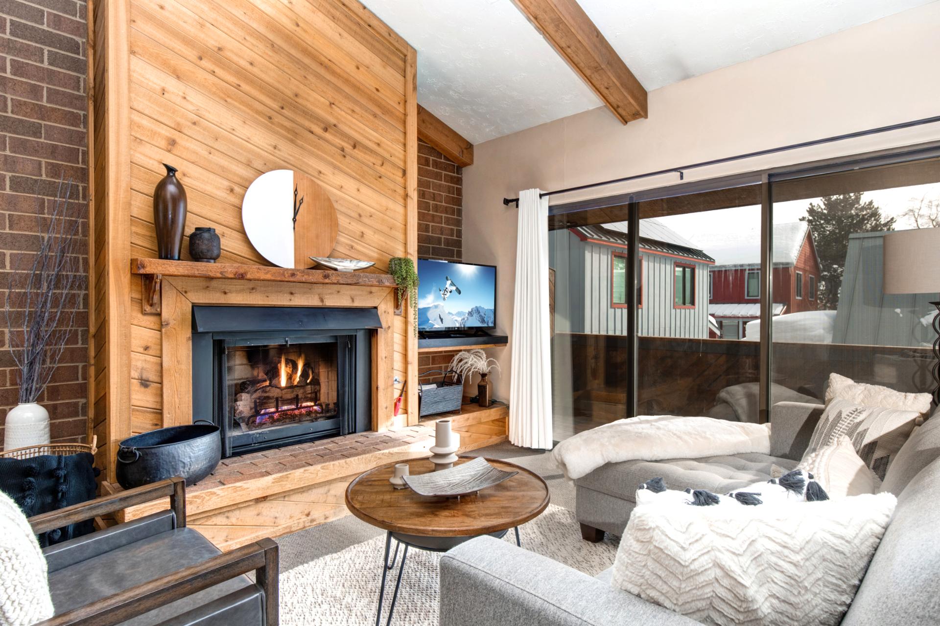 Gather around the gas fireplace in your living room with wood beams, smart TV, and patio access.