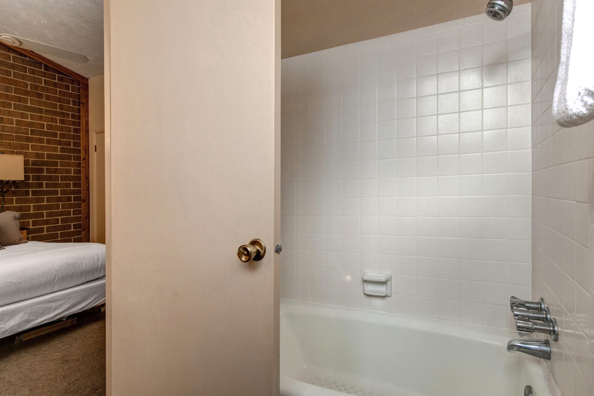 Clean and functional, this full bath serves Bedroom 1 with a shower/tub combo.
