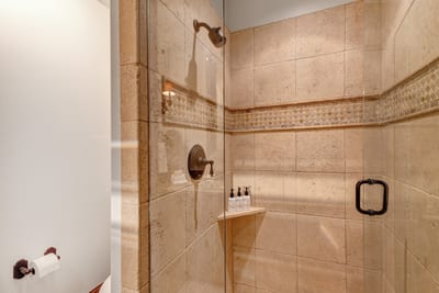 This guest bath includes a step-in tile shower and granite vanity with warm wood accents.