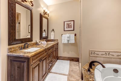 The spacious primary bath includes a double vanity, walk-in shower, and natural wood finishes. VIN-14