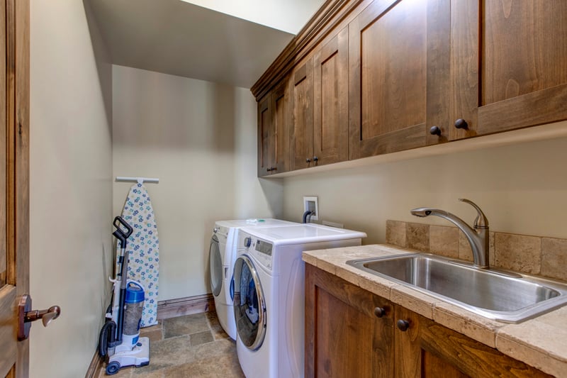 Efficient laundry room with rustic cabinetry, washer, dryer, and utility sink.