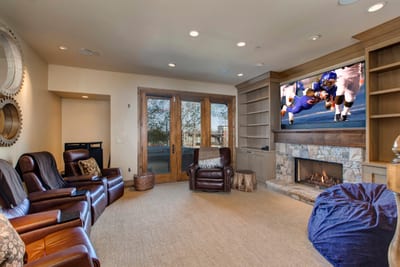 Lower-level family room includes plush seating and access to the private hot tub area with large TV