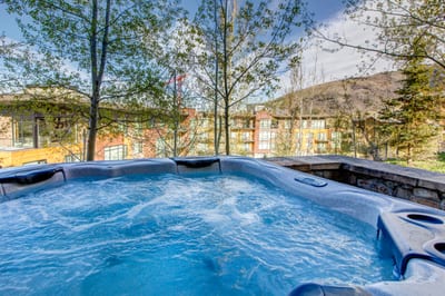 Bubbling hot tub with scenic mountain views and lush greenery.