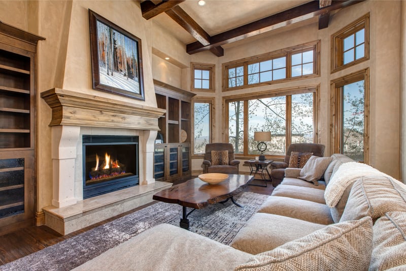 Gather in the main living room with vaulted ceilings, fireplace, and picture windows framing the mountain view.